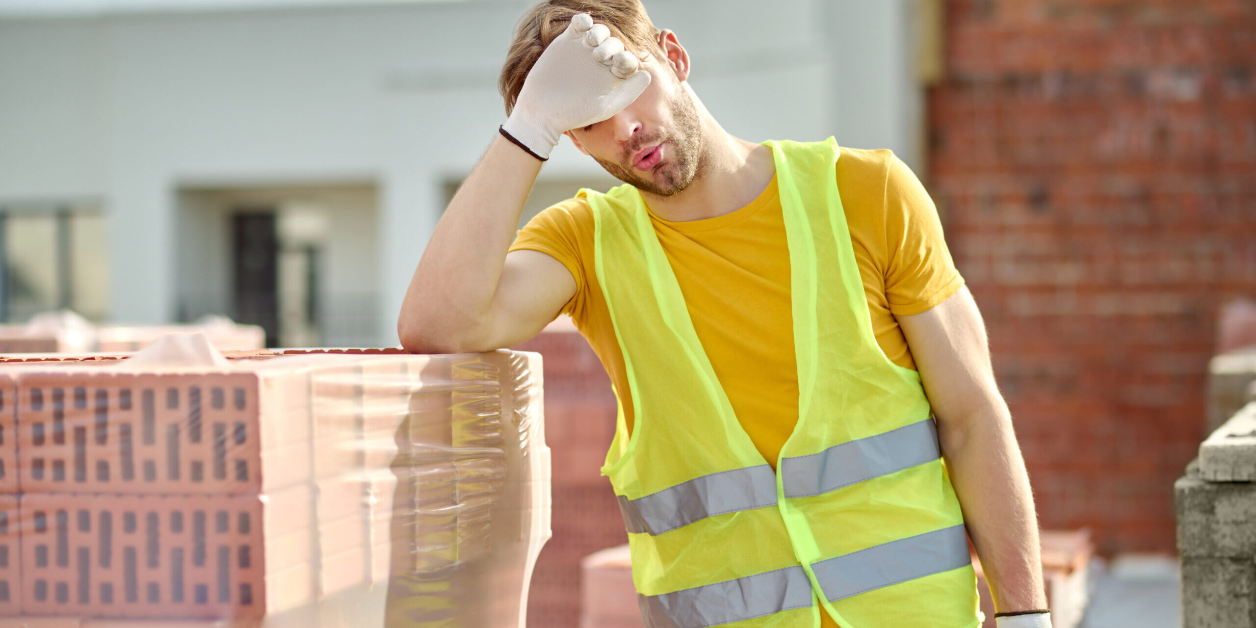 Tired worker touching face at construction site
